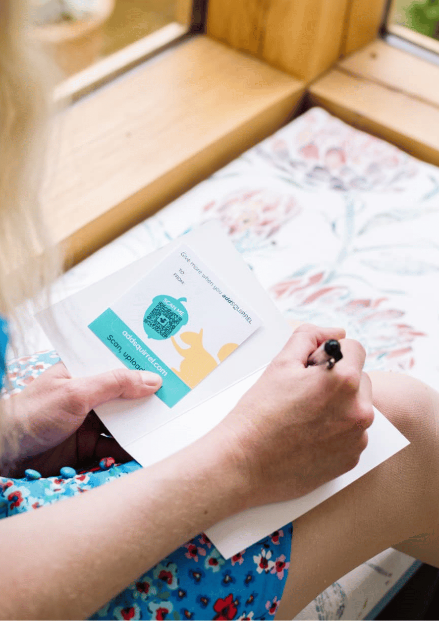 Someone writing a card with an addSQUIRREL QR code inside